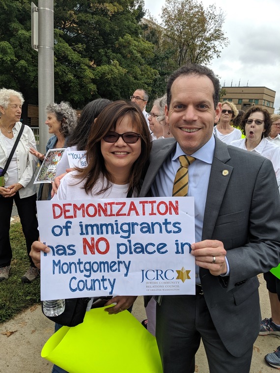 A picture of Councilmember Glass with an advocate holding a sign that reads "Demonization of immigrants has no place in Montgomery County"