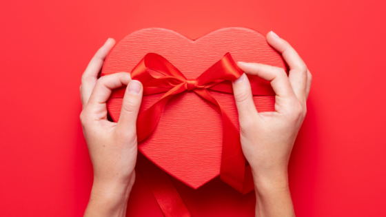 Hands tying red bow on red present box