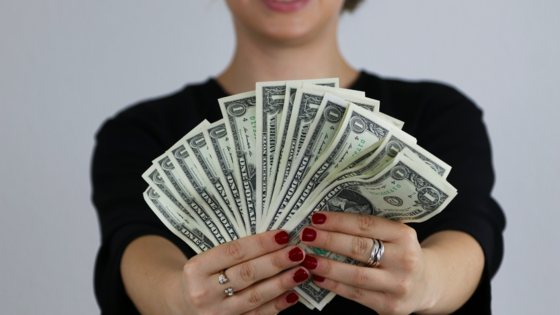 lady holding dollar bills between two hands spread out like a fan
