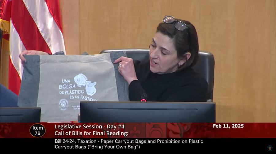 CP Stewart holds up a reusable bag while sitting at the Council dais.