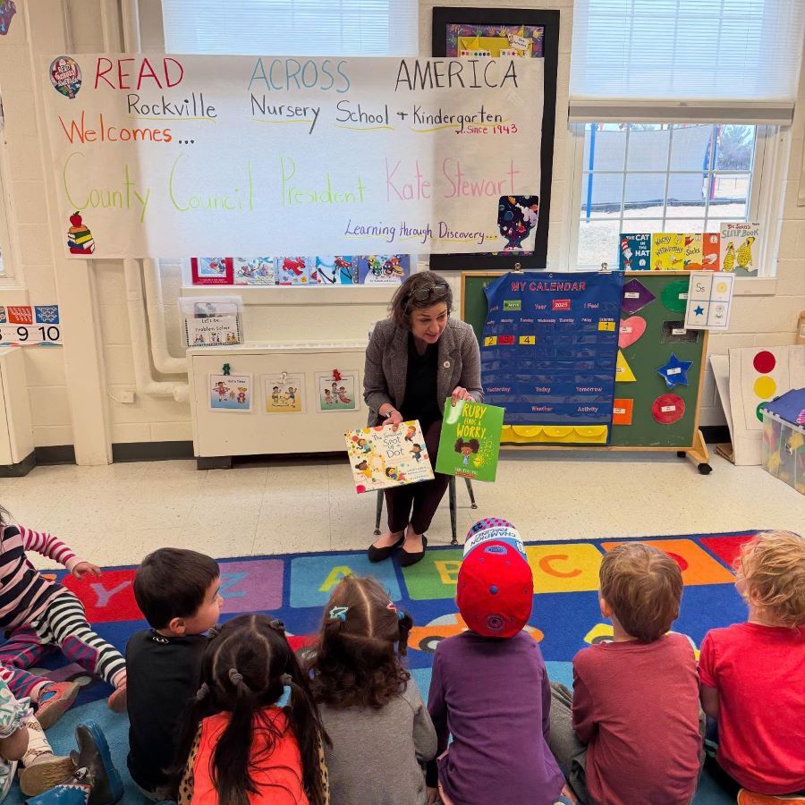 Council President Stewart reads to a group of small children in a classroom.