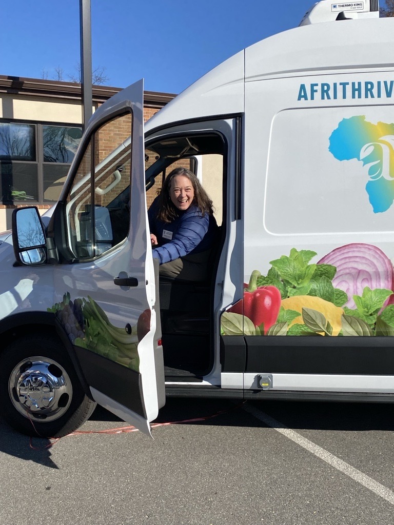 Picture of Heather Bruskin smiling while holding open the truck door in the front seat of the Afrithrive truck Picture of Heather Bruskin smiling while holding open the truck door in the front seat of the Afrithrive truck