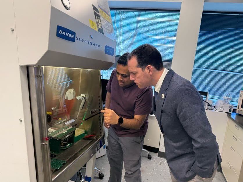 One of the leaders of Hememics Biotechnologies shows Councilmember Glass some of the equipment in the facility.