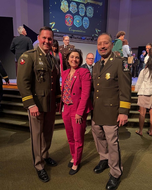 Council President Stewart poses with Chief Yamada and Reed in front of the awards stage.