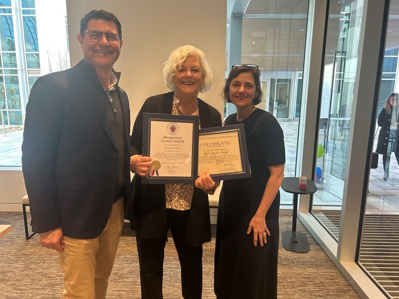 Councilmember Albornoz, Ms. Sinclair-Smith and CP Stewart smile for a photo and hold up a Council proclamation and certificate.