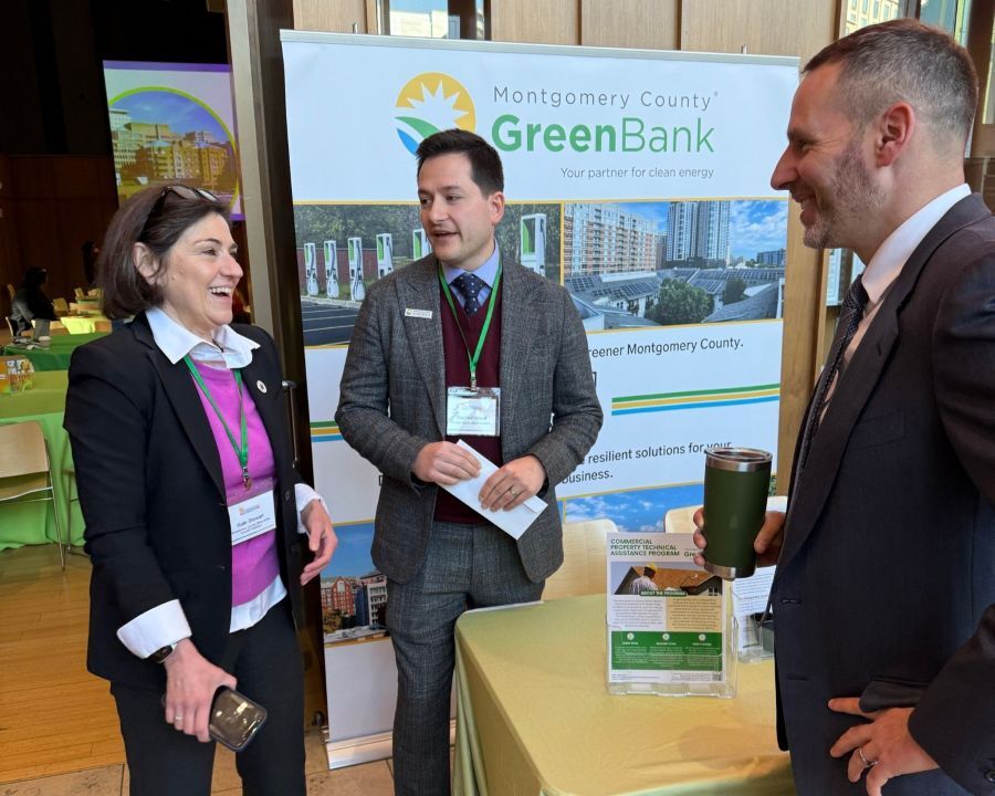 Council President Stewart speaks with county environmental leaders in front of a Montgomery County Green Bank table and banner.