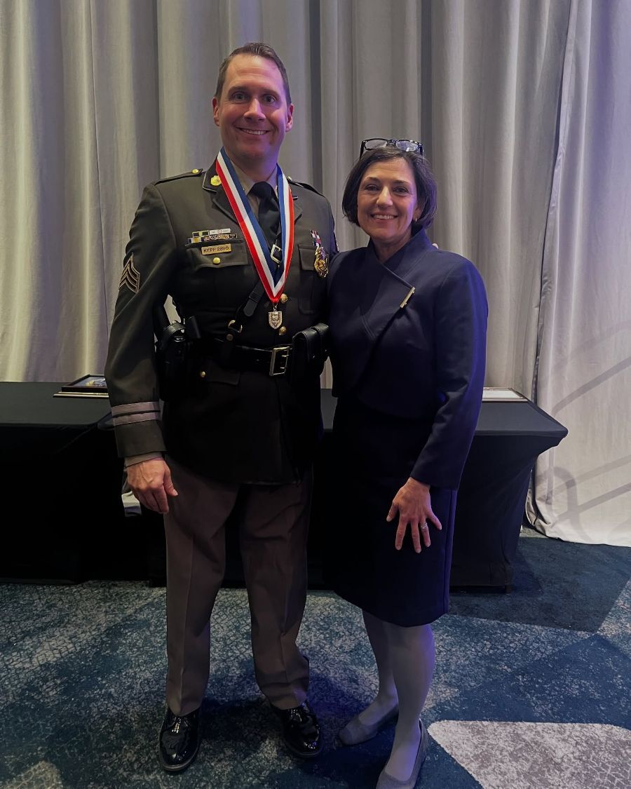 Sergeant Patrick Kepp and Council President Stewart smile for a photo. Sgt. Kepp proudly wears a gold medal award.