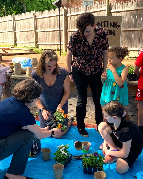 Council President Stewart and Delegate Charkoudian put plants into small pots with a resident and two children.