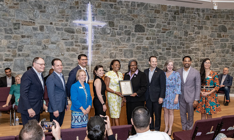 Councilmembers and Rev. Dr. Huggins smile for a photo and hold up a proclamation in the newly renovated Scotland AME Zion Church.