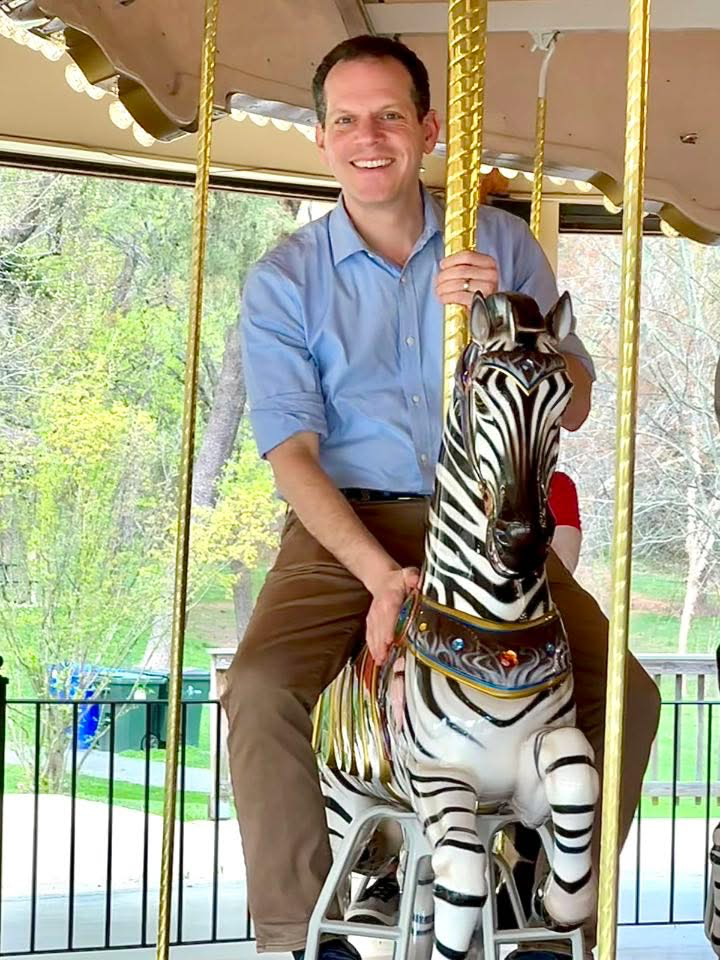 Councilmember Glass rides the new Wheaton Carousel on a zebra