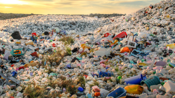 Sunrise over a large landfill filled with various types of discarded waste, highlighting the environmental issue of pollution.
