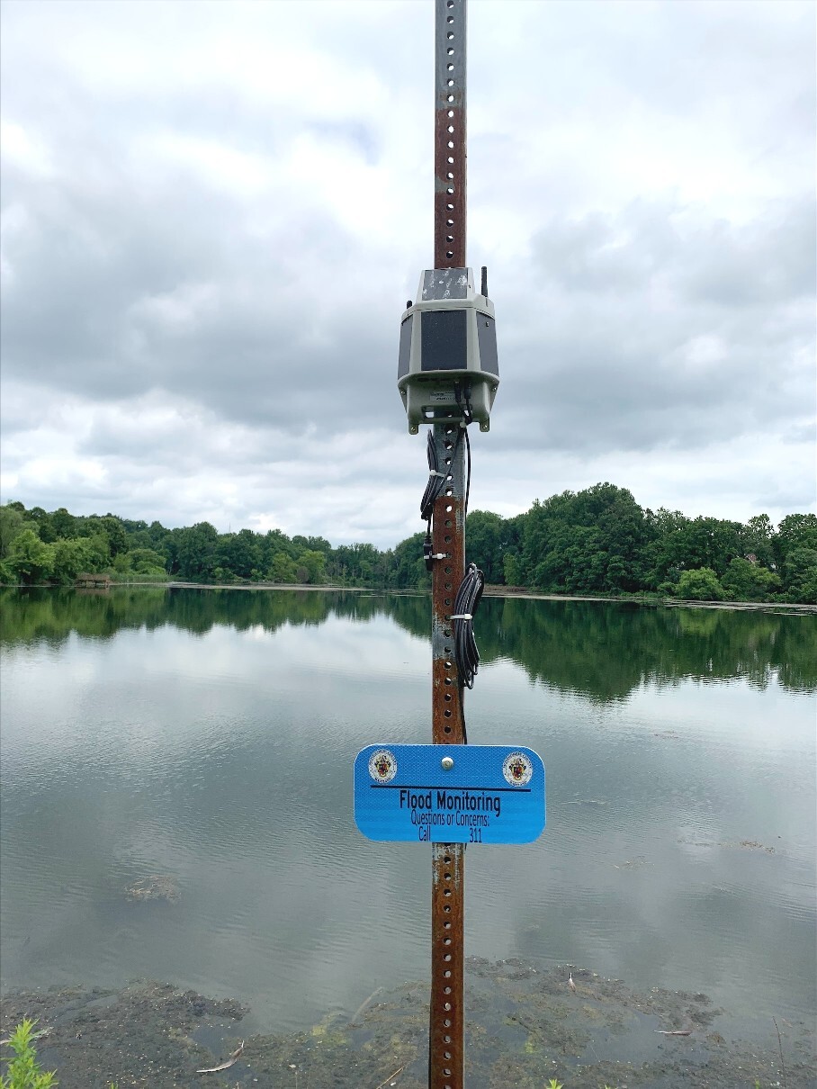 A flood monitoring sensor mounted on a pole above a body of water