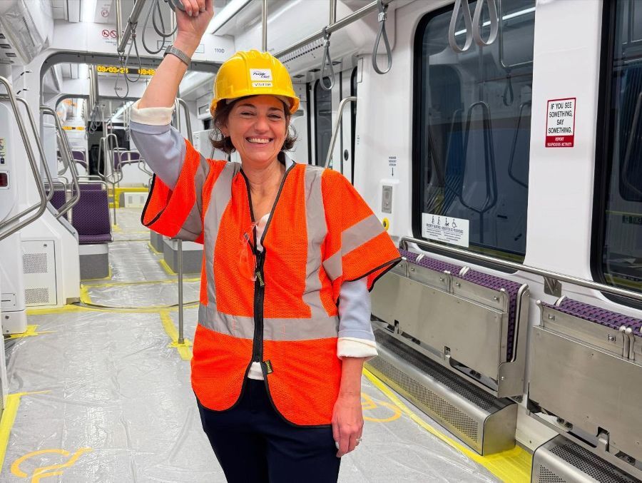 Council President Stewart wears a construction vest and hard hat inside of a Purple Line light rail car.