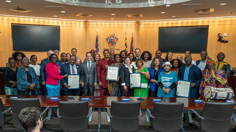 Participants and Council members present the African Heritage Month proclamation in the Council chamber.
