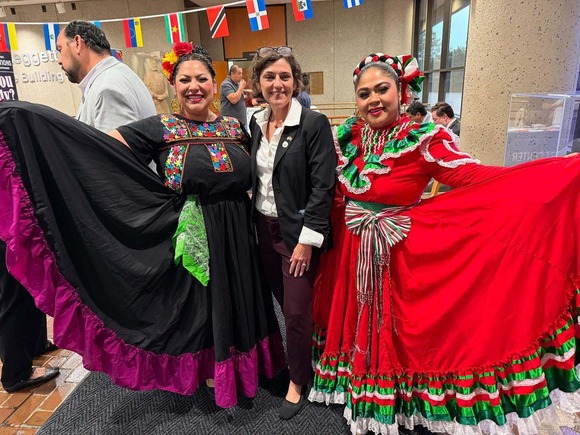 Council President Stewart at the Hispanic Heritage Month celebration with two folkloric dancers in traditional dresses.