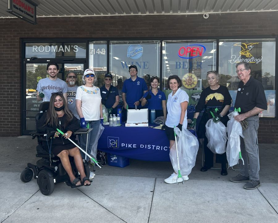 Community members gather at an outdoor Pike District table with trash bags, gloves and supplies for the community clean-up event.