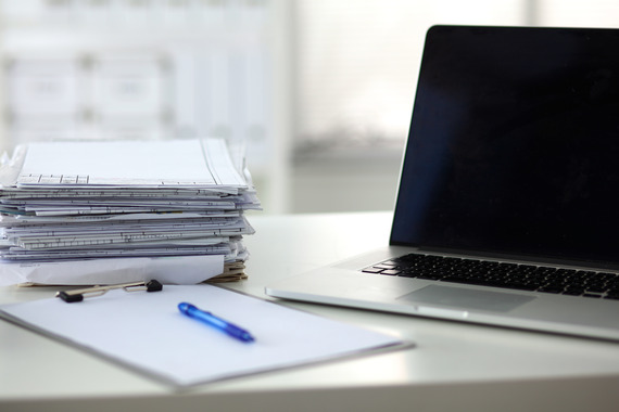 computer laptop piles of paper