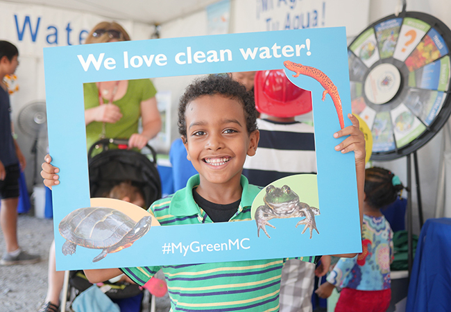 Boy with sign that says We Love Clean Water