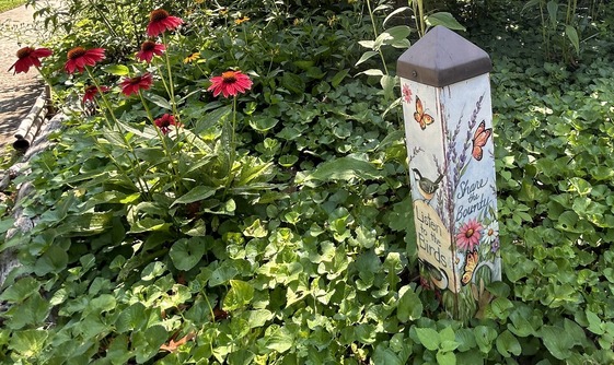 a handmade sign says Listen to the Birds, Share the Bounty