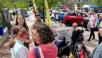 People standing on a street during at festival with electric vehicles in the background