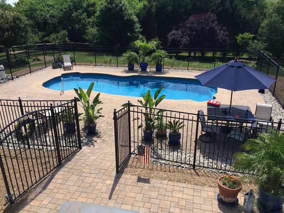 photo of a residential backyard in-ground pool and fence 
