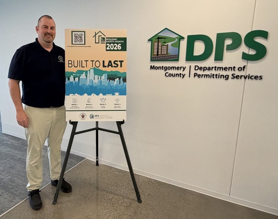 dps jeremy shupp stands next to building safety month poster 