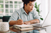 Woman sits at a laptop taking notes