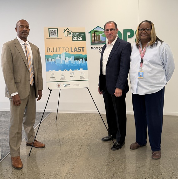 DPS Director, DPS Podcast host, and MCPS podcast guest standing next to Built to Last poster at DPS. 