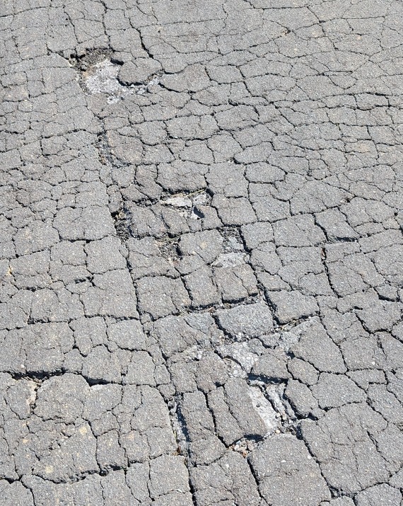 A picture of a street with cracks and fissures across its surface