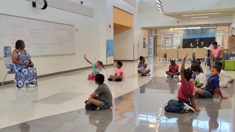 Partner sits with children for a school lesson