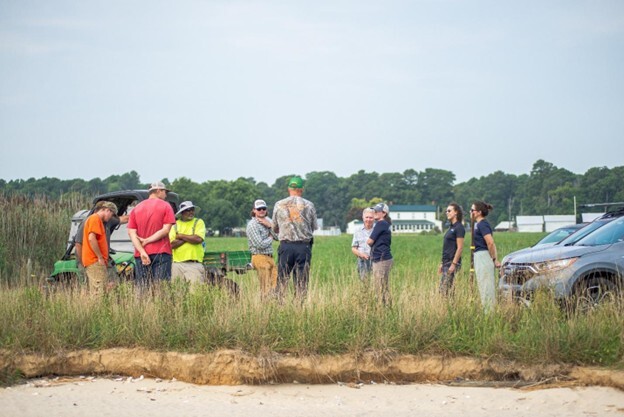 Landowners and project representatives discuss the Trossbach Farm Living Shoreline Project in a field.