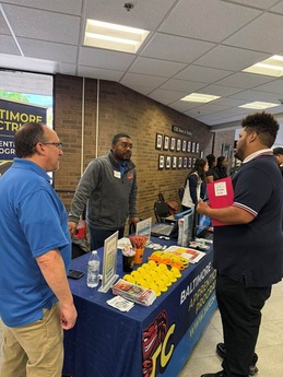 Image of people standing at a table learning about career opportunities through the port of Baltimore. 