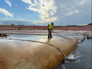 A worker manually agitates the geotube to improve drying efficiency at Cox Creek DMCF.