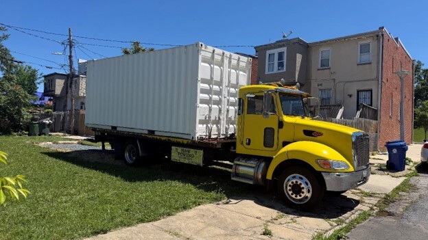 Yellow truck with white shipping container in a city 