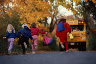 Stock image of children running towards a school bus on a fall day 