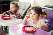 toddlers eating in a high chair