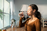 Photo of woman drinking glass of water in kitchen.