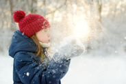 Young child playing in snow outside during winter weather.