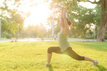 Foto de una mujer estirándose al aire libre en un día soleado.