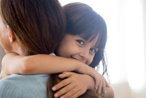 Un niño sonriendo y abrazando a su madre.