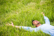 Una persona relajándose, tumbada en la hierba al aire libre.
