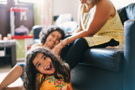 Una madre y dos niños pequeños sonriendo y jugando juntos en casa.