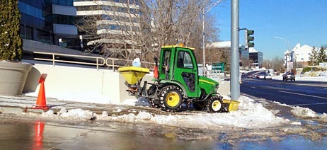 tractor removing snow on business sidewalk