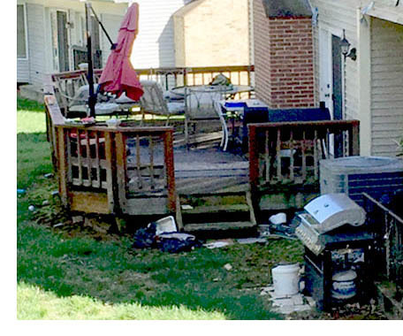 Broken umbrella on picnic table, trash and debris strewn over deck and yard