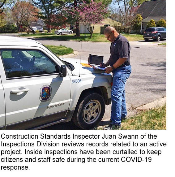 Juan conducts exterior inspection in the field with laptop on hood of car