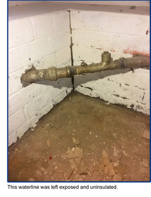 This waterline was left exposed and uninsulated. Photo of pipe crossing a room corner (exiting and inserting) at a diagonal into cinderblock wall.