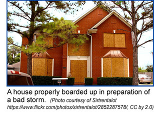 Brick house with windows boarded up in preparation of a bad storm.