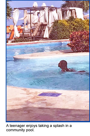 A teenage girl enjoys taking a splash in a community pool.
