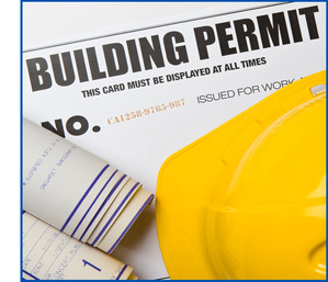 Building Permit words on paper with rolled architectural plans and yellow hard hat