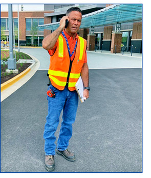 Building Inspector Mike Metz at the job site for an inspection, stops to answer a call.